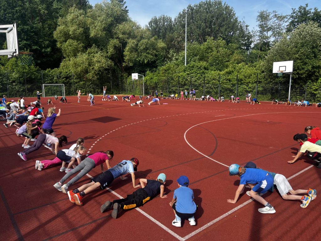 Kinder machen sich auf dem Sportplatz warm.